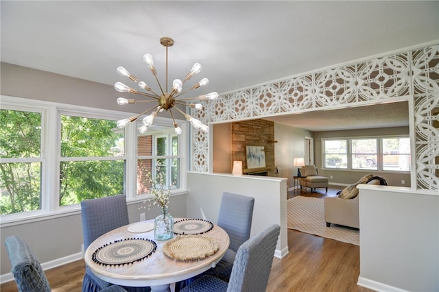 dining room featuring wood-type flooring, a healthy amount of sunlight, and an inviting chandelier