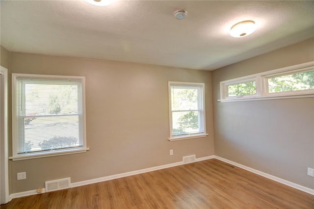 spare room with light hardwood / wood-style floors and a textured ceiling