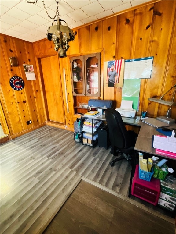 home office with wood walls, dark wood-type flooring, and a notable chandelier