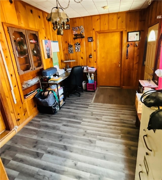 home office featuring a chandelier, wooden walls, and dark wood-type flooring