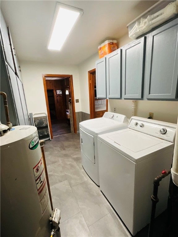 clothes washing area with washer and clothes dryer, cabinets, and gas water heater