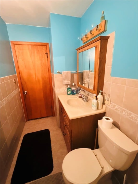 bathroom featuring vanity, tile walls, and toilet