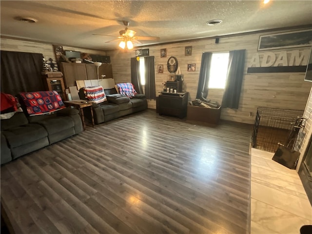 living room featuring a textured ceiling, wooden walls, ceiling fan, and dark hardwood / wood-style floors