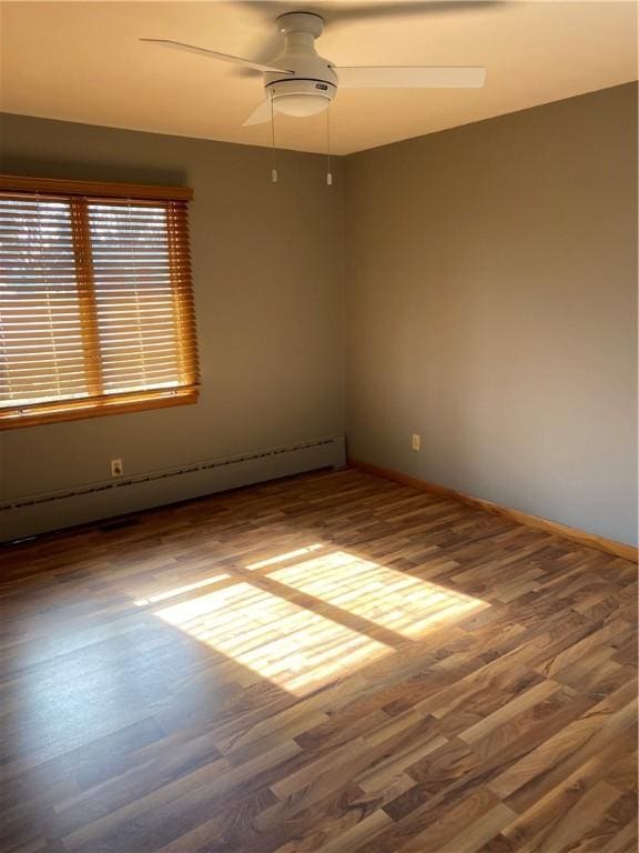 spare room featuring a baseboard heating unit, hardwood / wood-style flooring, and ceiling fan