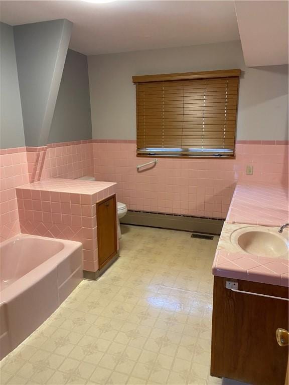 bathroom with toilet, tile walls, a baseboard radiator, vanity, and a bath