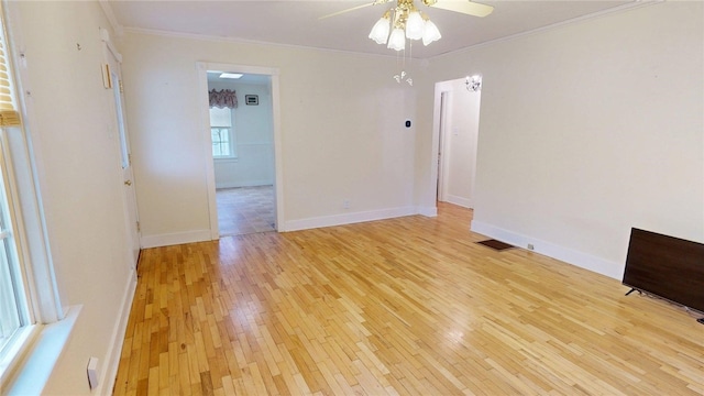 empty room featuring visible vents, a ceiling fan, light wood-type flooring, crown molding, and baseboards