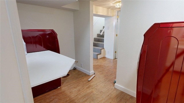 corridor with baseboards, wood finished floors, and stairs