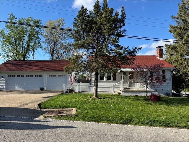 view of front of home featuring an attached garage, driveway, a front lawn, and a chimney
