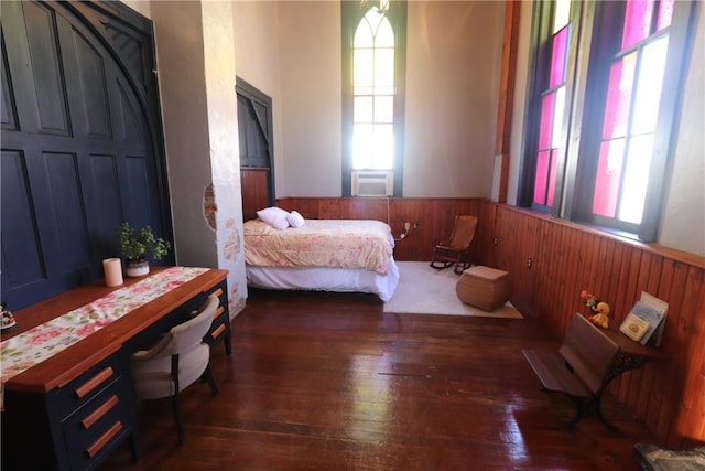 bedroom with dark wood-type flooring and wooden walls