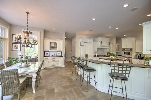 4140 S Lake Ct, Decatur, IL 62521 - kitchen featuring dark countertops, double oven, a kitchen bar, and a notable chandelier