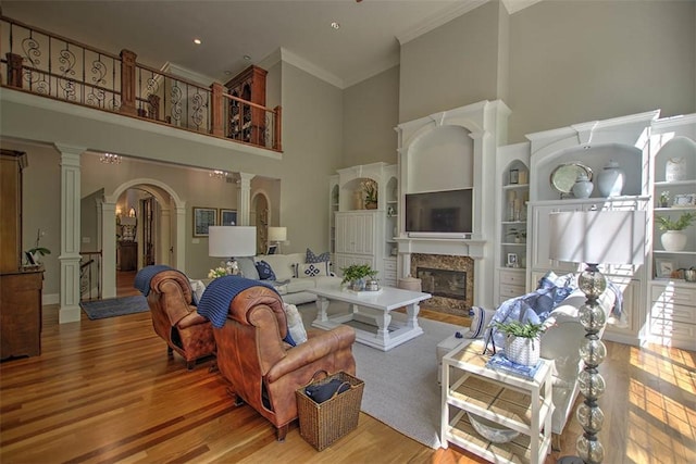 4140 S Lake Ct, Decatur, IL 62521 - living room featuring wood finished floors, crown molding, a towering ceiling, arched walkways, and a glass covered fireplace