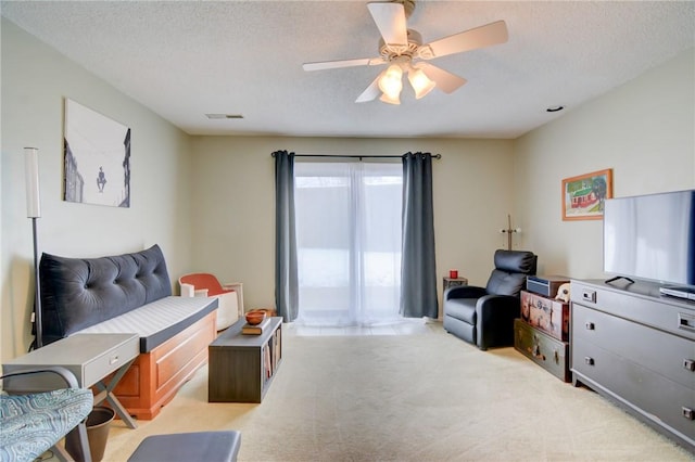 carpeted living room with a textured ceiling and ceiling fan