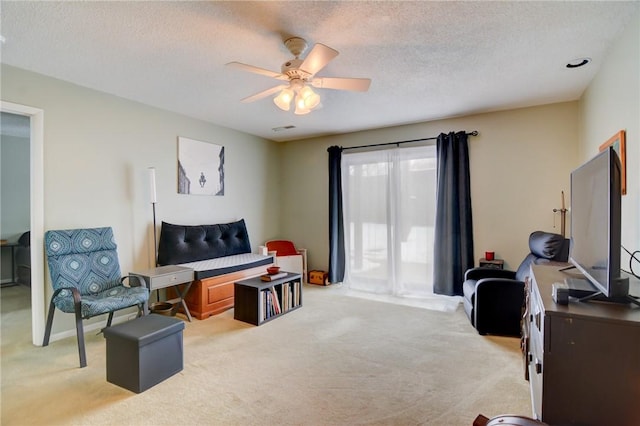 sitting room with a textured ceiling, ceiling fan, and light carpet