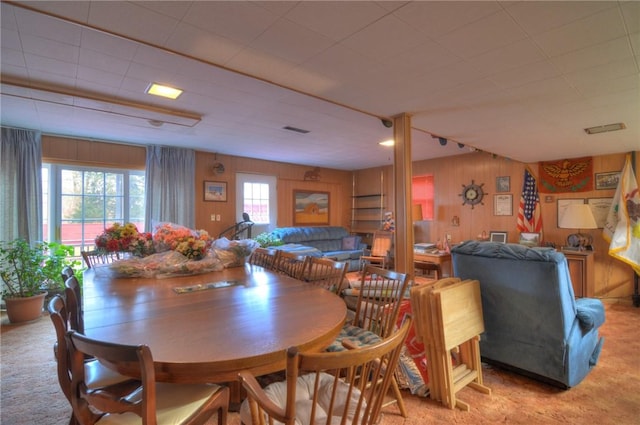 dining room featuring light colored carpet, visible vents, and wooden walls