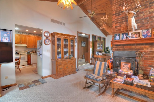 living area with baseboards, visible vents, light colored carpet, a fireplace, and high vaulted ceiling