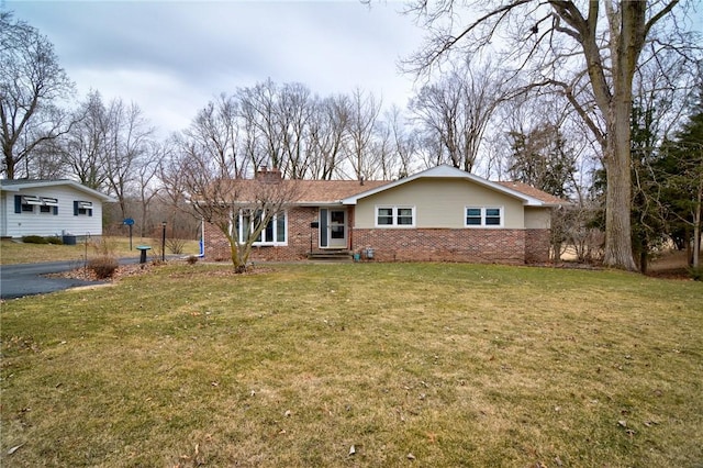 view of front of house with a chimney, a front lawn, and brick siding