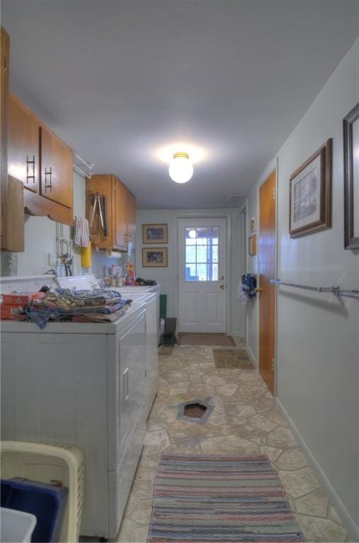 laundry area featuring washer and dryer, cabinet space, and baseboards