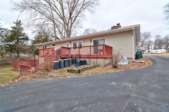 view of front of home featuring a chimney, fence, and a wooden deck