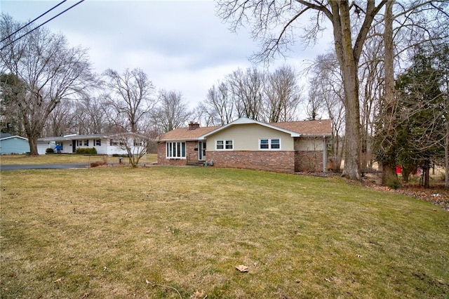 view of front of home with brick siding, a chimney, and a front lawn