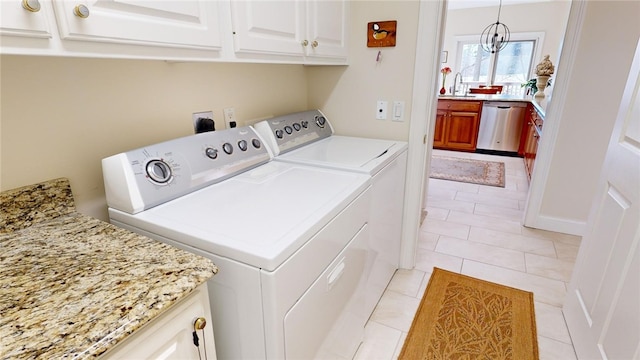 clothes washing area with cabinets, washing machine and dryer, sink, and light tile patterned flooring