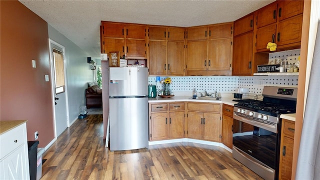 kitchen with a textured ceiling, decorative backsplash, dark hardwood / wood-style flooring, and stainless steel appliances