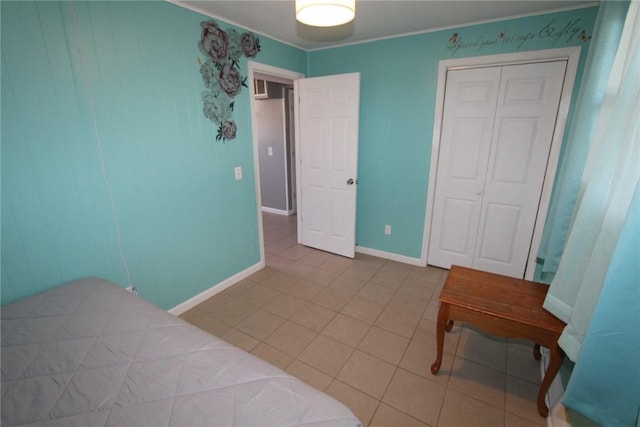 tiled bedroom with crown molding, baseboards, and a closet