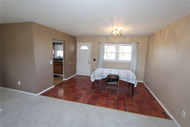 carpeted dining room with baseboards, a chandelier, a sink, and tile patterned floors