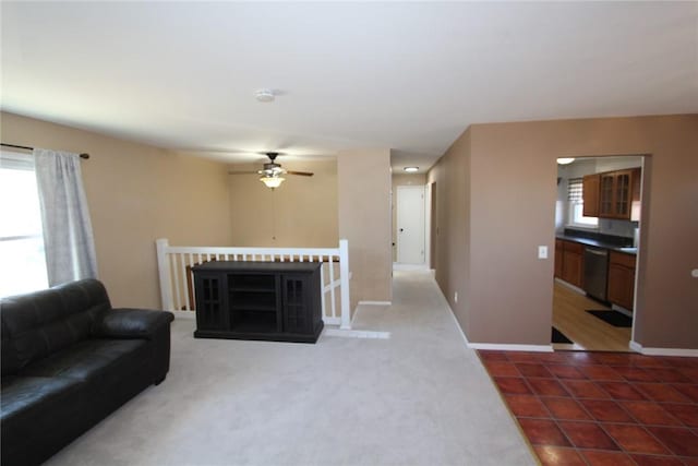 living room featuring a ceiling fan, dark tile patterned flooring, plenty of natural light, and baseboards