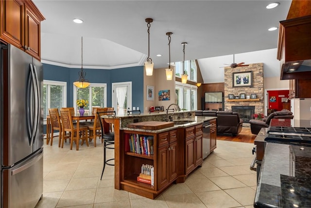 11107 E Cambridge Ln, Effingham, IL 62401 - kitchen featuring appliances with stainless steel finishes, ceiling fan, a fireplace, light tile patterned floors, and a kitchen breakfast bar