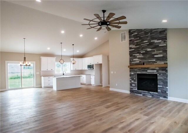 3812 Sonny Ln, Danville, IL 61832 - unfurnished living room featuring a ceiling fan, a stone fireplace, light wood-type flooring, a chandelier, and high vaulted ceiling