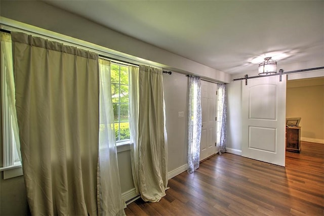 3985 E Cerro Gordo St, Decatur, IL 62521 - spare room featuring a barn door, dark wood-type flooring, healthy amount of natural light, and baseboards
