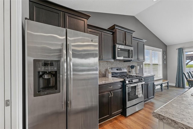 1121 Meadow Brook Ct, Mattoon, IL 61938 - kitchen featuring appliances with stainless steel finishes, vaulted ceiling, dark brown cabinetry, decorative backsplash, and light wood-style flooring