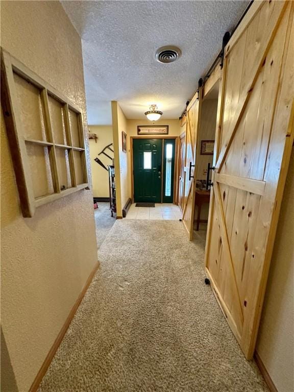 interior space featuring a barn door, a textured ceiling, and light carpet