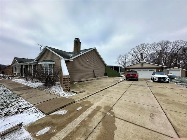 view of snow covered exterior featuring a garage and an outdoor structure