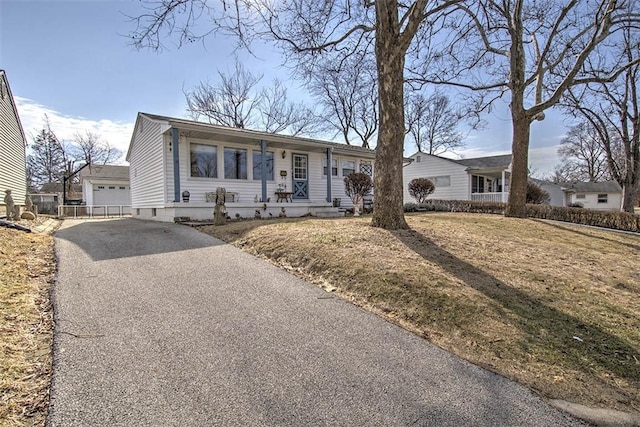 ranch-style house featuring aphalt driveway, a front lawn, and an outdoor structure