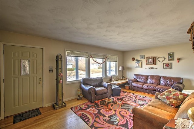 living area featuring a textured ceiling, light wood-style flooring, and baseboards