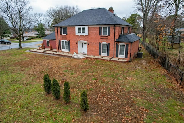 colonial-style house with central air condition unit and a front lawn