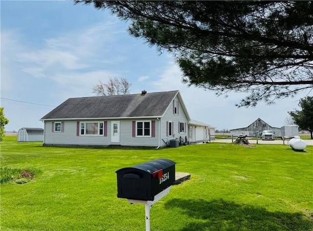 cape cod house with a front yard, central AC unit, and an outbuilding