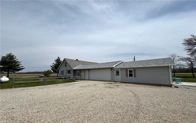 view of front of property featuring an attached garage, fence, and gravel driveway