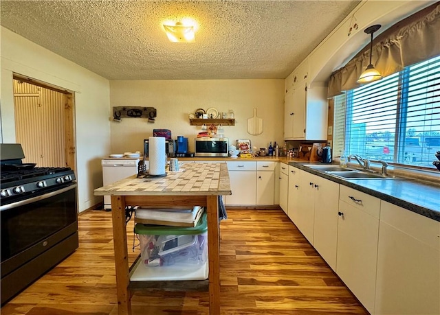 kitchen with range with gas cooktop, stainless steel microwave, a textured ceiling, and a sink