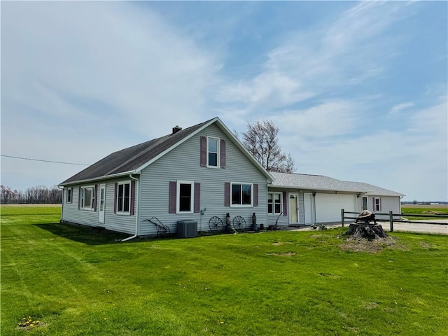 back of house featuring a garage, a yard, driveway, and cooling unit
