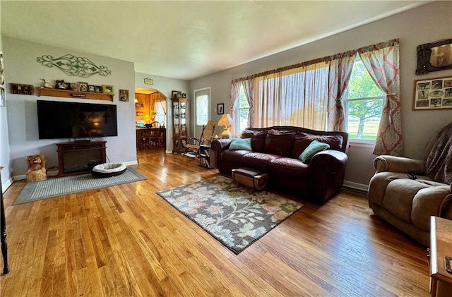 living area featuring arched walkways, wood finished floors, and baseboards