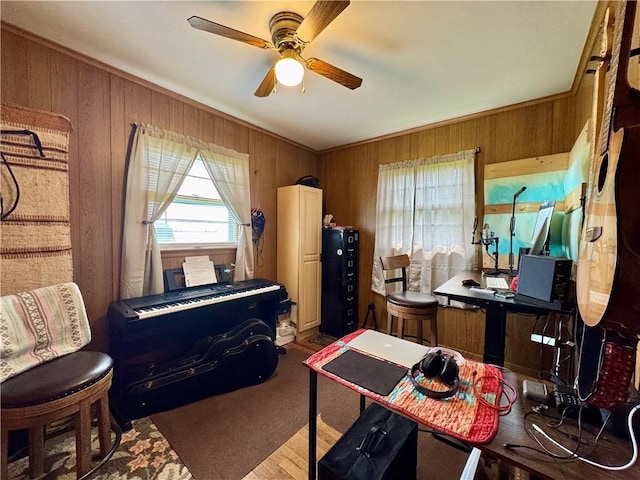 home office featuring wood walls, a wealth of natural light, and a ceiling fan