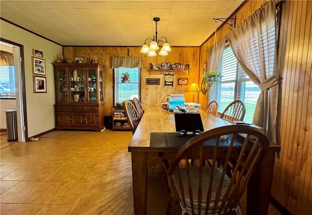 dining room featuring ornamental molding, wood walls, and a chandelier