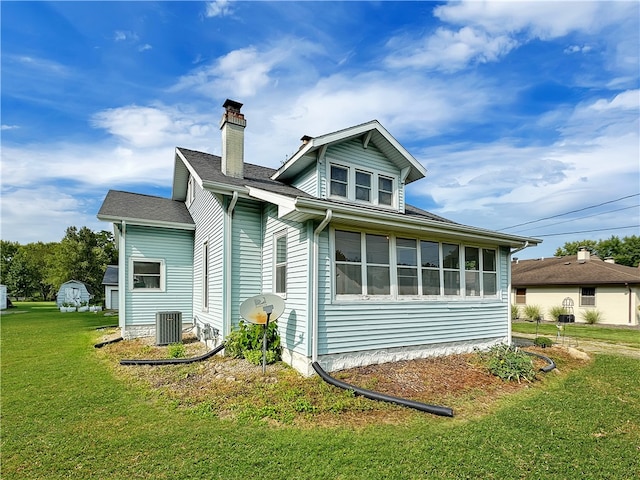 view of side of property with a lawn, central AC, and a sunroom