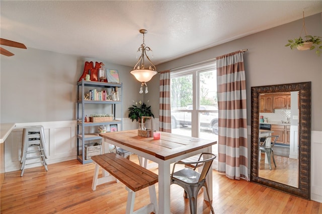 530 Sunset Dr, Mt Zion, IL 62549 - dining space with light wood-style floors, a ceiling fan, and a wainscoted wall