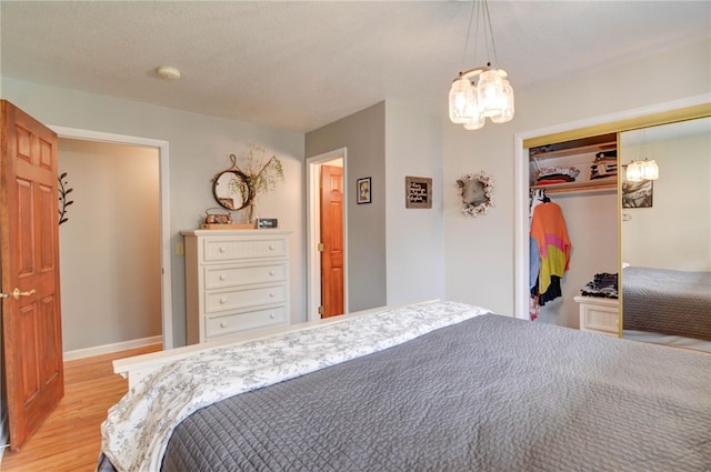 530 Sunset Dr, Mt Zion, IL 62549 - bedroom featuring light wood-style floors, a chandelier, a closet, and baseboards