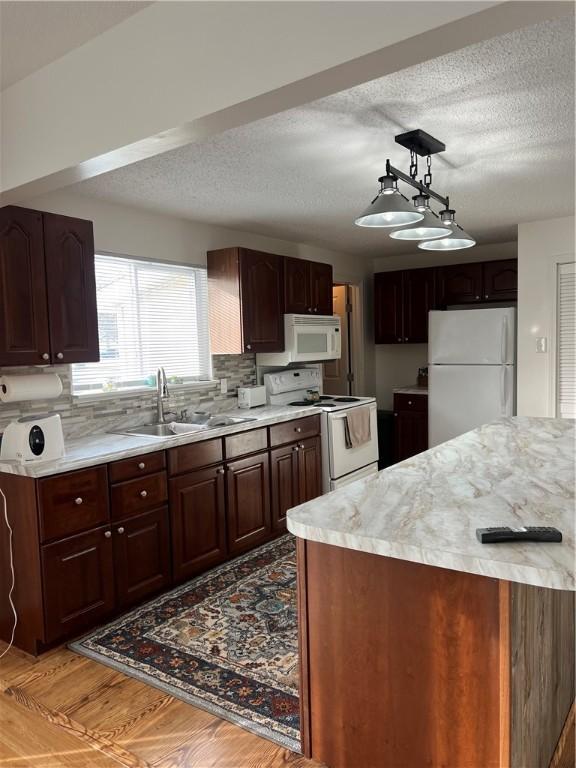 kitchen featuring sink, white appliances, light hardwood / wood-style floors, decorative backsplash, and decorative light fixtures