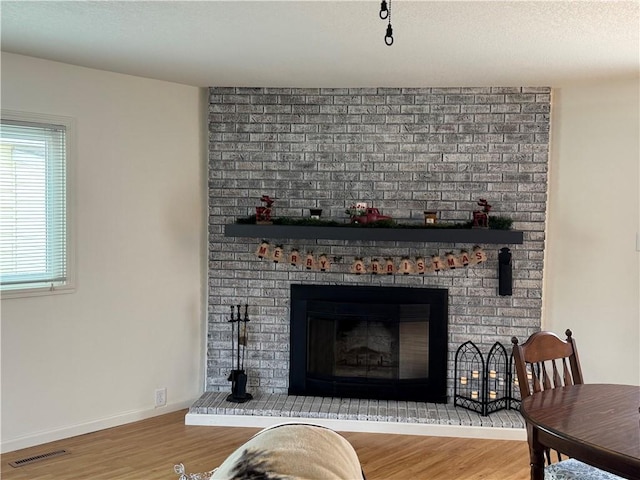 living room with a brick fireplace and hardwood / wood-style flooring