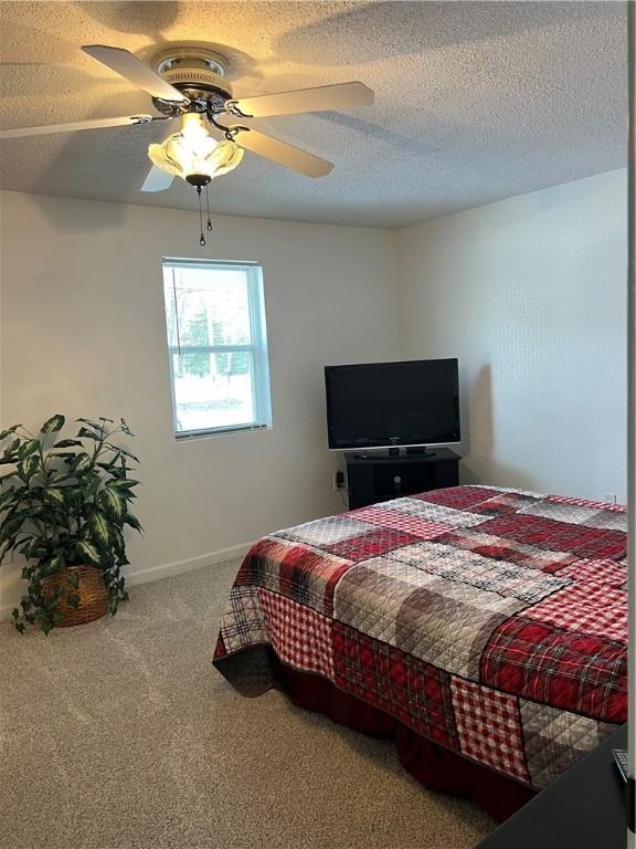 carpeted bedroom with a textured ceiling and ceiling fan